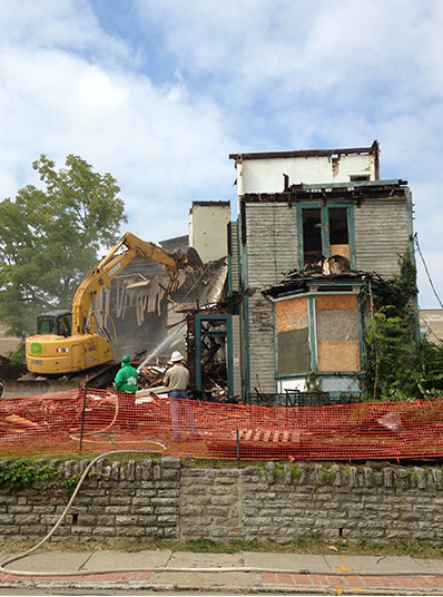 Old two-story home being deconstructed by an excavator