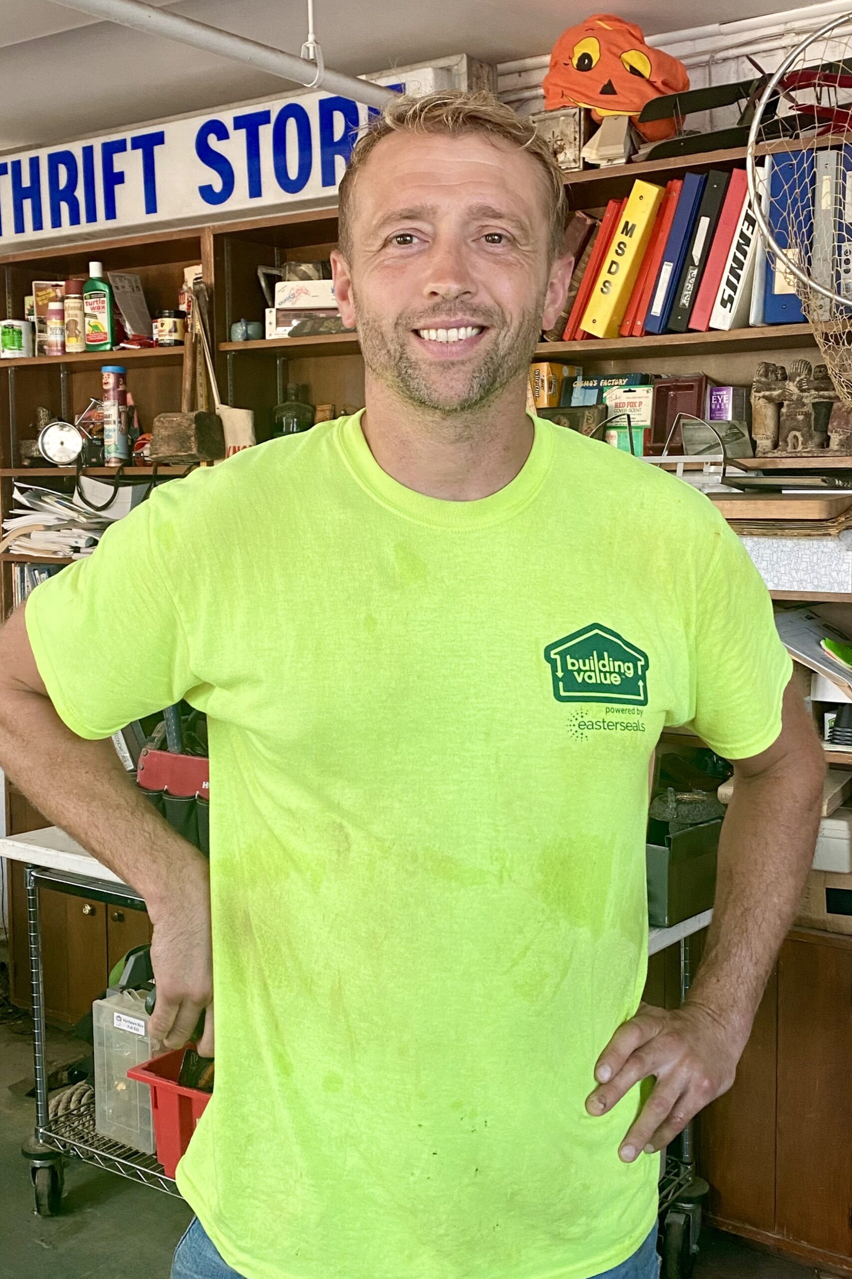 A Building Value team member in a bright yellow Building Value t-shirt smiling inside a Cincinnati thrift store.