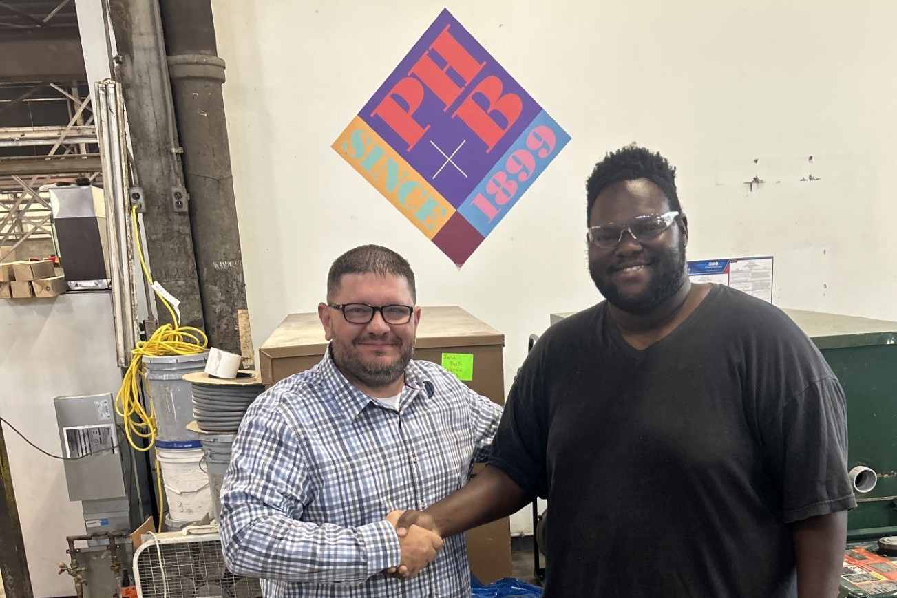 Karl Edwards, the 100th graduate of Building Value's career program, shaking hands with his new employer at the PH+B facility.